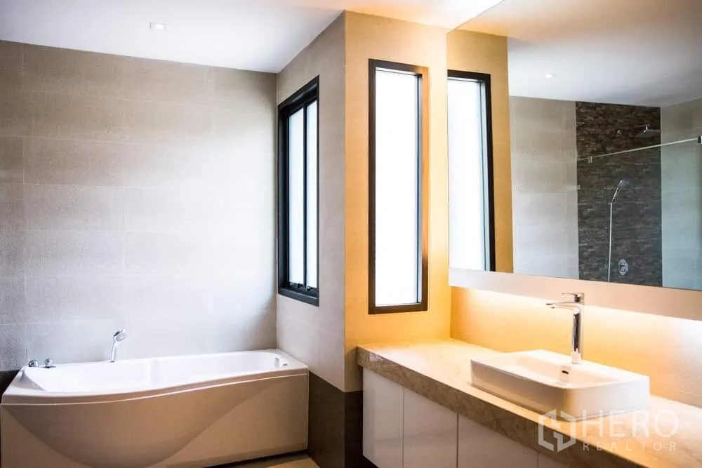 Detached House for rent in Khlong Toei, Bangkok - Contemporary bathroom with bathtub, long vanity, large mirror and glass shower.