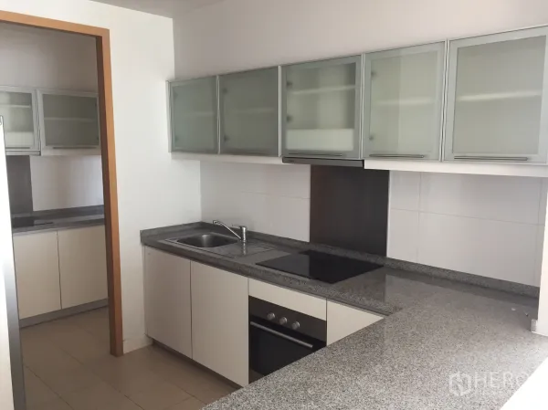 Condominium for rent in Khlong Toei, Bangkok - Modern kitchen zone with glass-front cabinets, built-in oven, electric cooktop and granite worktops.