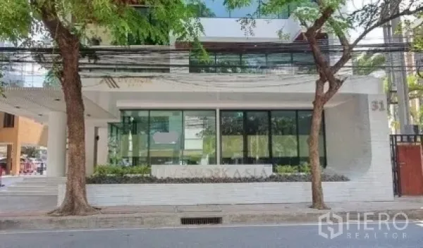 Retail Space for rent in Khlong Toei, Bangkok - Full frontage of a modern building showing a ground-floor glass retail space, mature street trees, and a city street view.