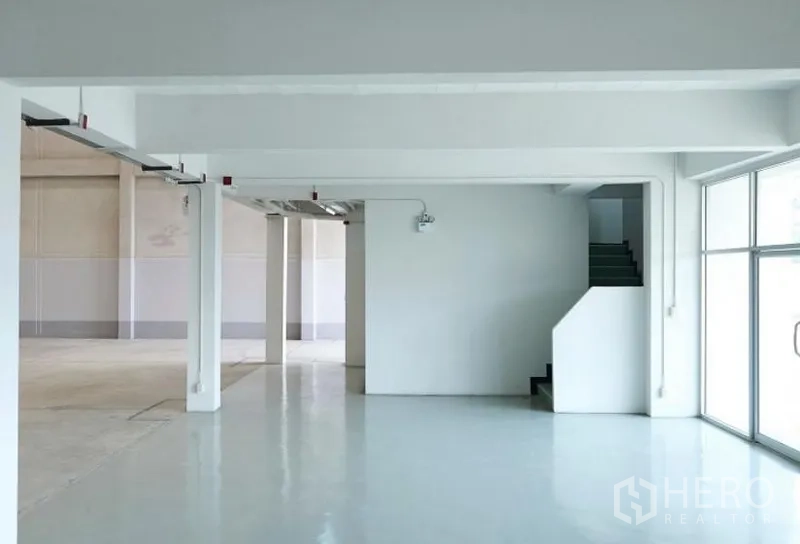Factory for rent in Pluak Daeng, Rayong - Clean production and packing area with epoxy floor, columns and stair access beside glass frontage.