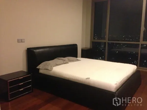 คอนโด ขายในWatthana, Bangkok - ห้องนอนมาสเตอร์เตียงหนัง พื้นไม้ และหน้าต่างกระจกสูงมองเห็นวิวเมืองยามค่ำคืน