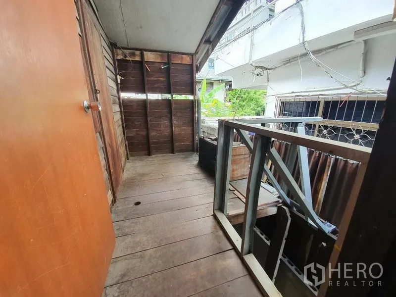 独立式住宅 出租在Sathon, Bangkok - 狭长的有顶阳台，木地板与金属栏杆，临巷景观。