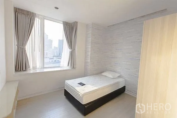 Condominium for rent in Huai Khwang, Bangkok - Bright second bedroom with single bed, window seat and city view.