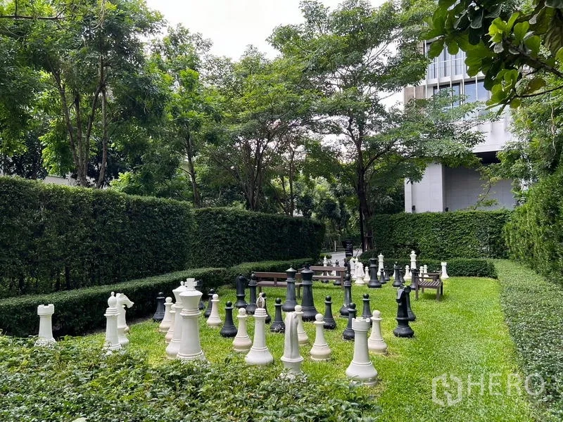 Condominium for sale - Lawn garden featuring a giant chess set surrounded by hedges and trees.