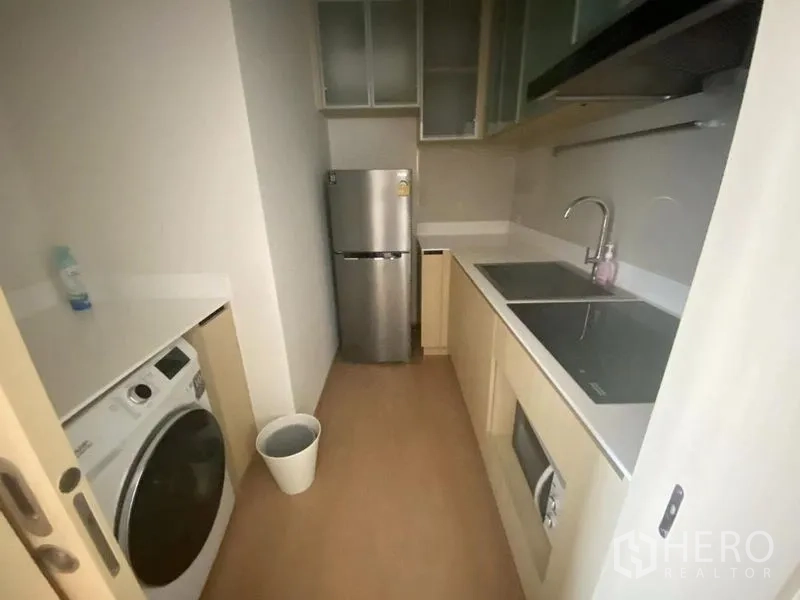 公寓 出租在Watthana, Bangkok - 独立封闭式厨房，配感应灶、微波炉、不锈钢冰箱、洗衣机与白色台面。