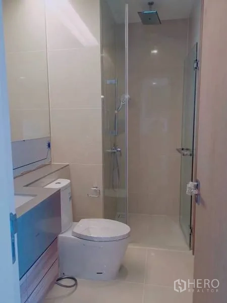 Condominium for rent or sale in Watthana, Bangkok - Clean bathroom with glass shower enclosure, rain head, vanity and toilet.