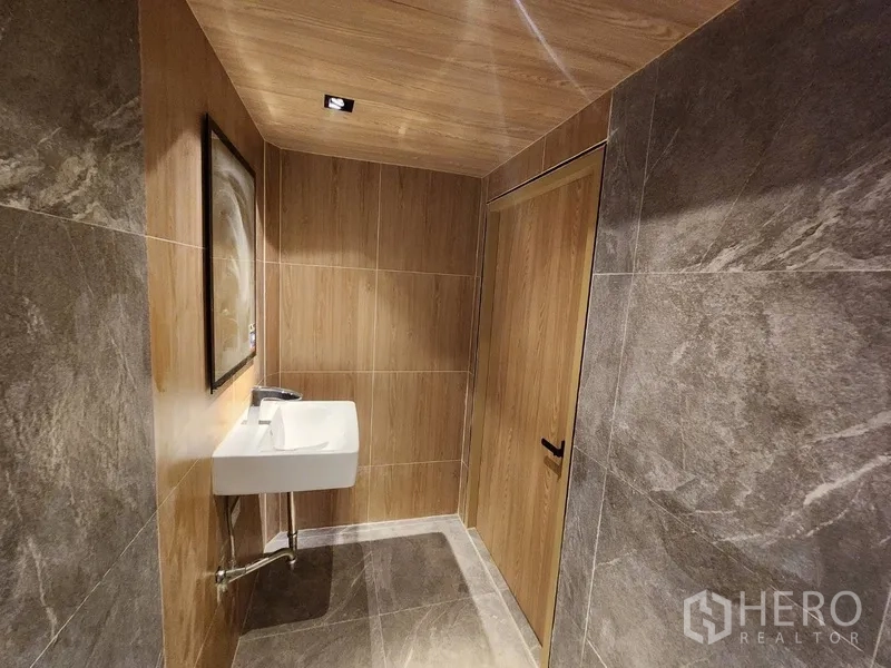 Retail Space for rent in Pathum Wan, Bangkok - Restroom finished with wood accents, stone-look tiles and wall-mounted sink.