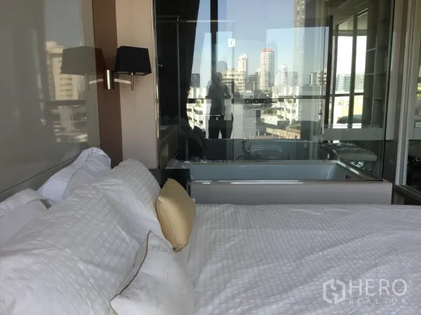 Condominium for rent in Khlong Toei, Bangkok - City-view bedroom with glass partition to bathroom featuring a built-in bathtub.