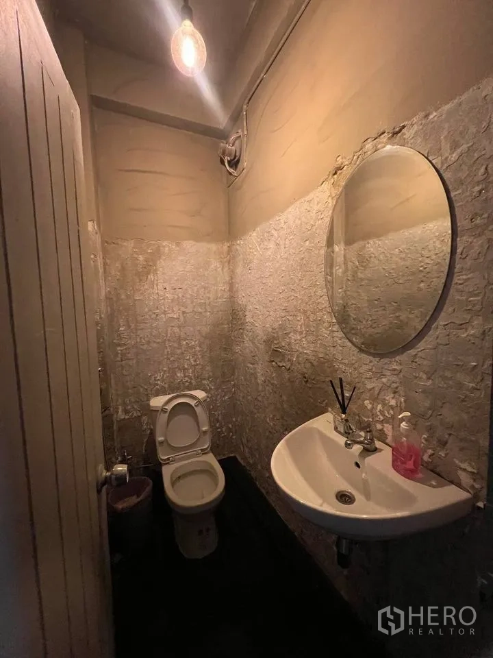 Shophouse for rent in Watthana, Bangkok - Guest restroom with round mirror, pedestal sink and toilet.