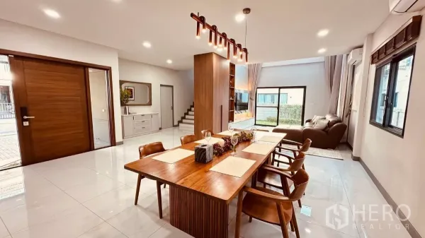 独立式住宅 出租在Bang Phli, Samut Prakan - 开放式客餐厅，木质餐桌与吊灯，落地滑门通向花园