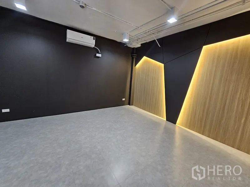 Retail Space for rent - Minimalist room with wood accent panels and warm backlighting on a dark feature wall.