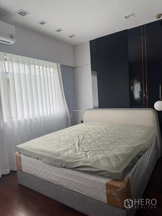Detached House for rent in Lat Krabang, Bangkok - Bright bedroom with large bed, sheer curtains and a glossy accent wall.