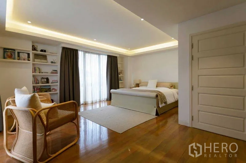 Home Office for sale in Watthana, Bangkok - Bedroom with built-in shelves, large window drapes and warm recessed lighting.