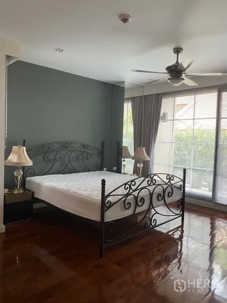 房间 出租在Pathum Wan, Bangkok - 主卧配锻铁床与吊扇，整面落地窗带百叶