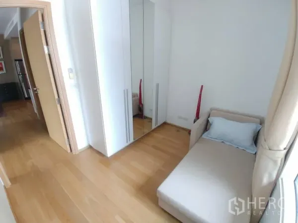 Condominium for rent or sale in Watthana, Bangkok - Cozy second bedroom with single bed and mirrored wardrobe by the window.