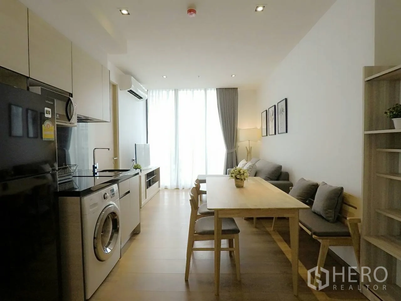 Condominium for rent or sale in Khlong Toei, Bangkok - Open-plan living, dining, and kitchen with sofa, dining table, built-in cabinets, and washing machine.