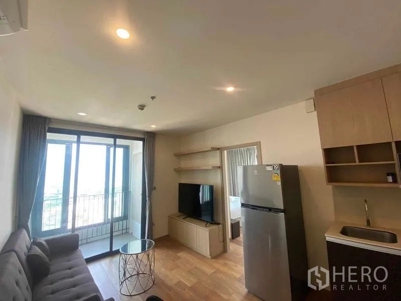 公寓 出租或出售在Ratchathewi, Bangkok - 明亮客厅，配沙发与电视柜，推拉门通往阳台。