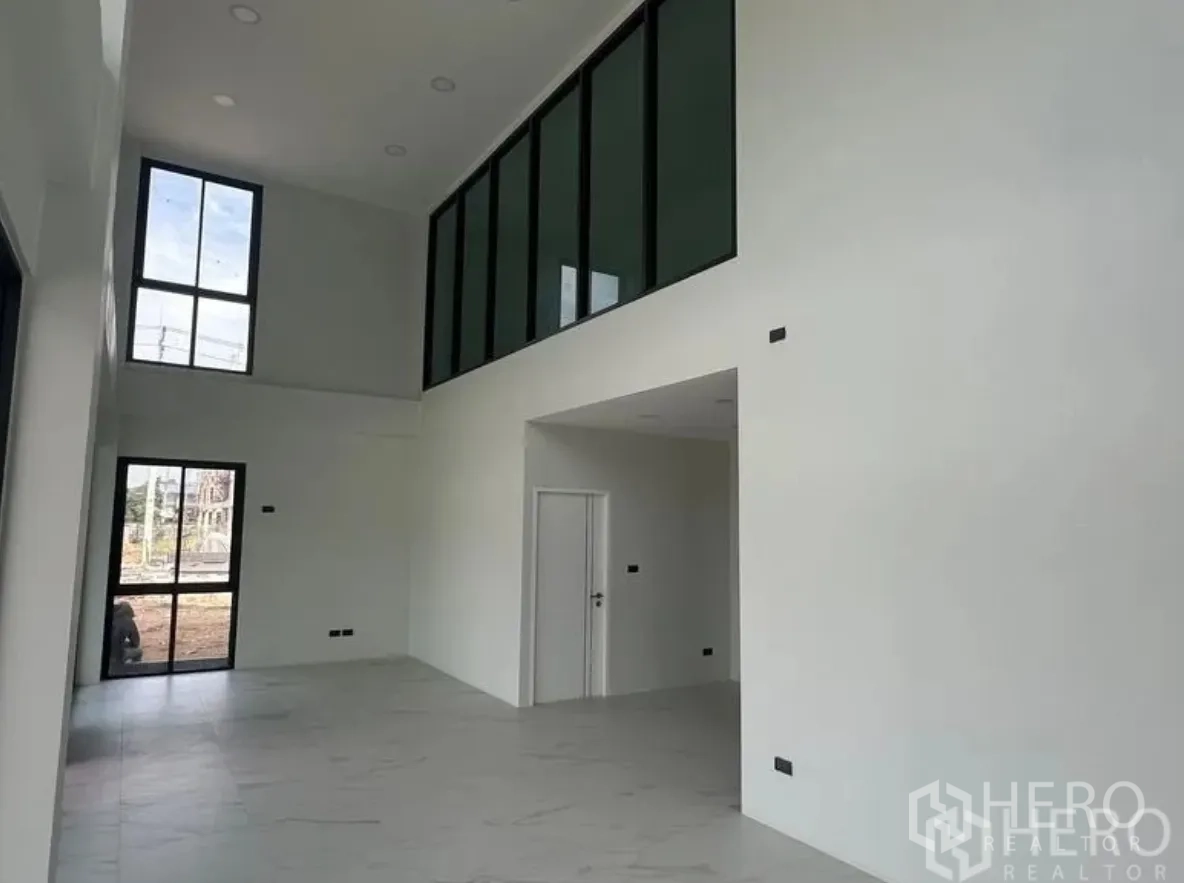 仓库 for sale in Lam Luk Ka, Pathum Thani - 挑高双层大堂，白墙、瓷砖地面与夹层内窗。