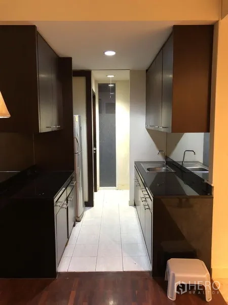 Detached House for rent in Wang Thonglang, Bangkok - Galley kitchen with dark cabinetry, black stone countertops, sink, and refrigerator.