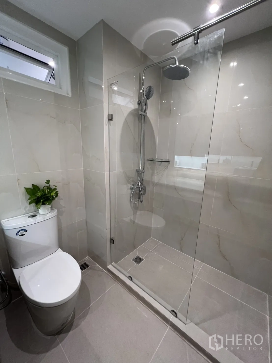 Condominium for rent in Yan Nawa, Bangkok - Bathroom showing glass-enclosed shower with rain head beside the toilet.