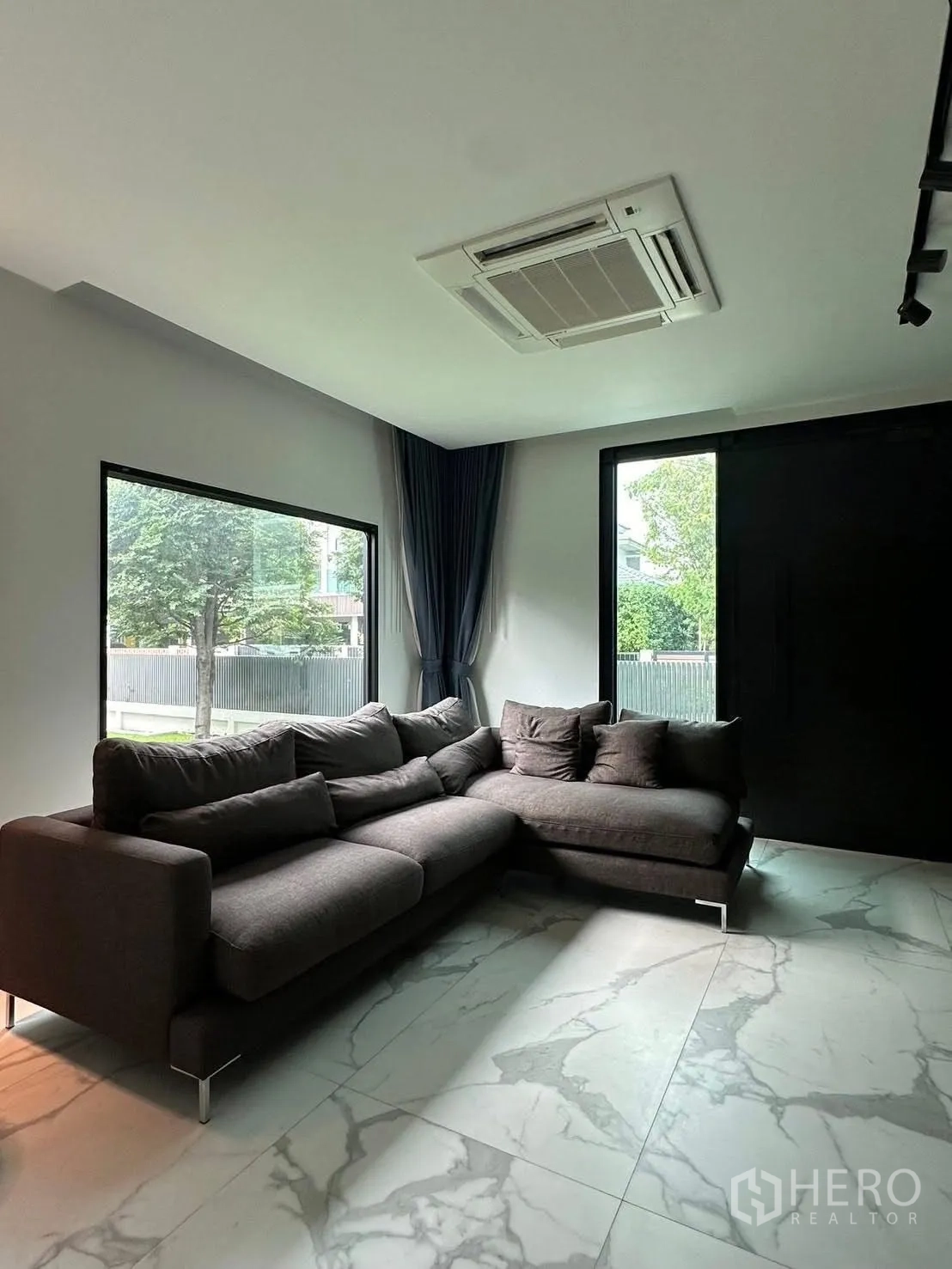 独立式住宅 出租在Lat Krabang, Bangkok - 家庭起居室，L型沙发、大窗与天花嵌入式空调。
