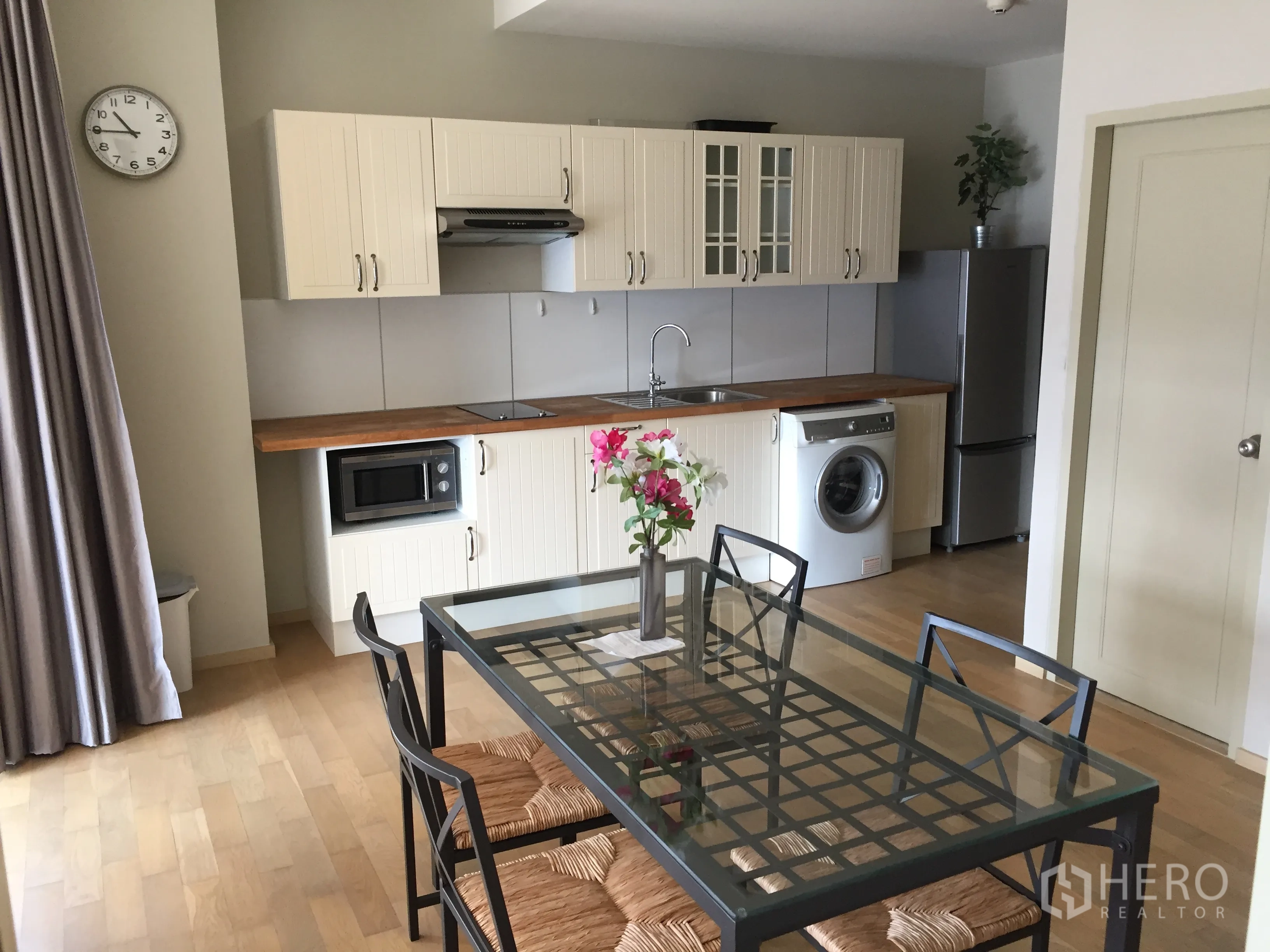Condominium for rent or sale in Watthana, Bangkok - Modern kitchenette with wood countertop, fridge, microwave, washer and a glass dining table.
