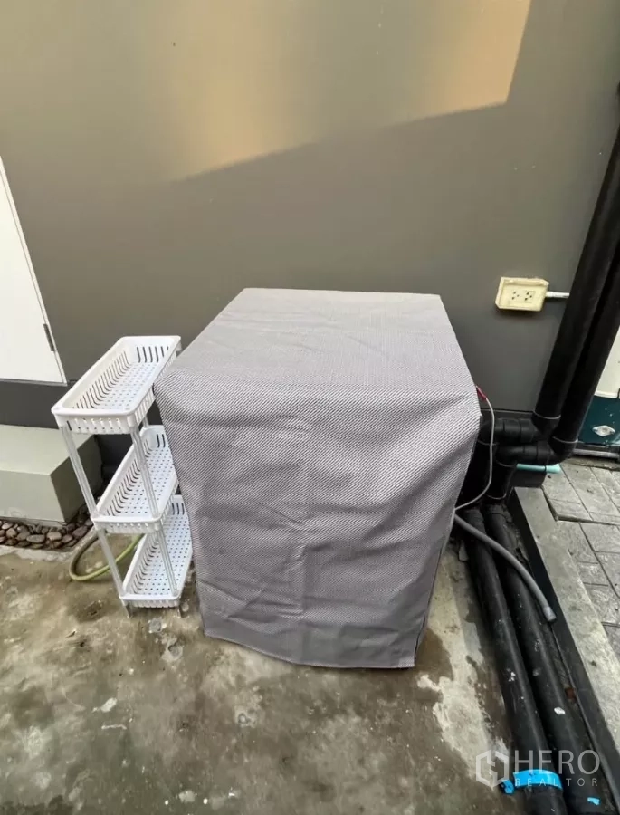 独立式住宅 出租在Prawet, Bangkok - 室外家务区，带防尘罩的洗衣机和置物架。