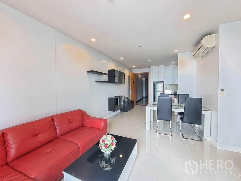 公寓 出租在Ratchathewi, Bangkok - 客厅配红色皮沙发、悬浮置物架与餐区，筒灯照明。