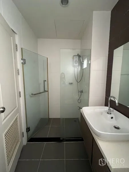 Townhouse for rent in Bang Kapi, Bangkok - Clean bathroom with glass-enclosed shower, wall-mounted water heater, and vanity.