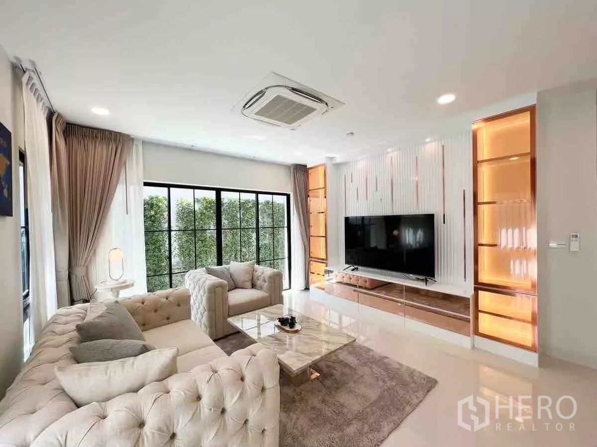 Detached House for rent or sale in Saphan Sung, Bangkok - Bright living room with tufted sofas, large TV wall and floor-to-ceiling windows