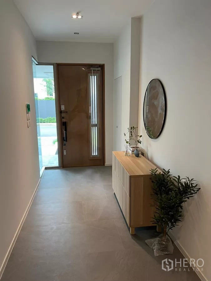 Detached House for rent in Saphan Sung, Bangkok - Entry hallway with wooden door, console cabinet and round wall mirror.