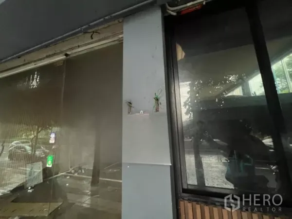 店屋 出租在Khlong Toei, Bangkok - 店面玻璃与立柱特写，可见安装位与街景倒影。