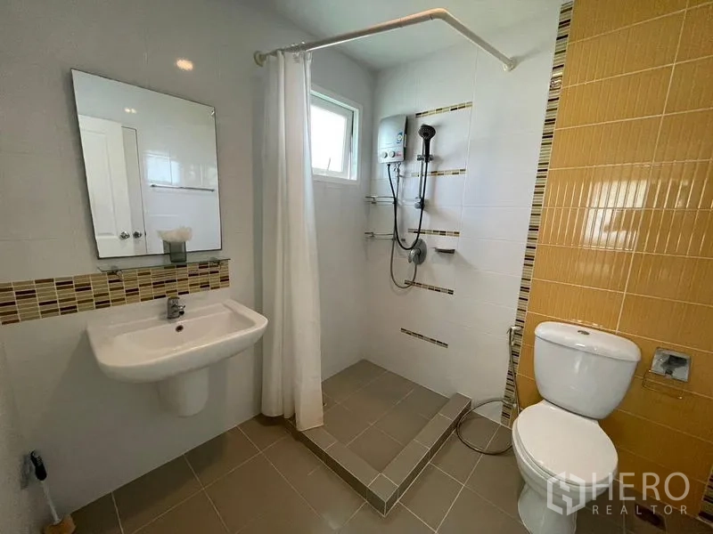 Detached House for sale in Lam Luk Ka, Pathum Thani - Bright bathroom with walk-in shower, yellow accent wall and water heater.