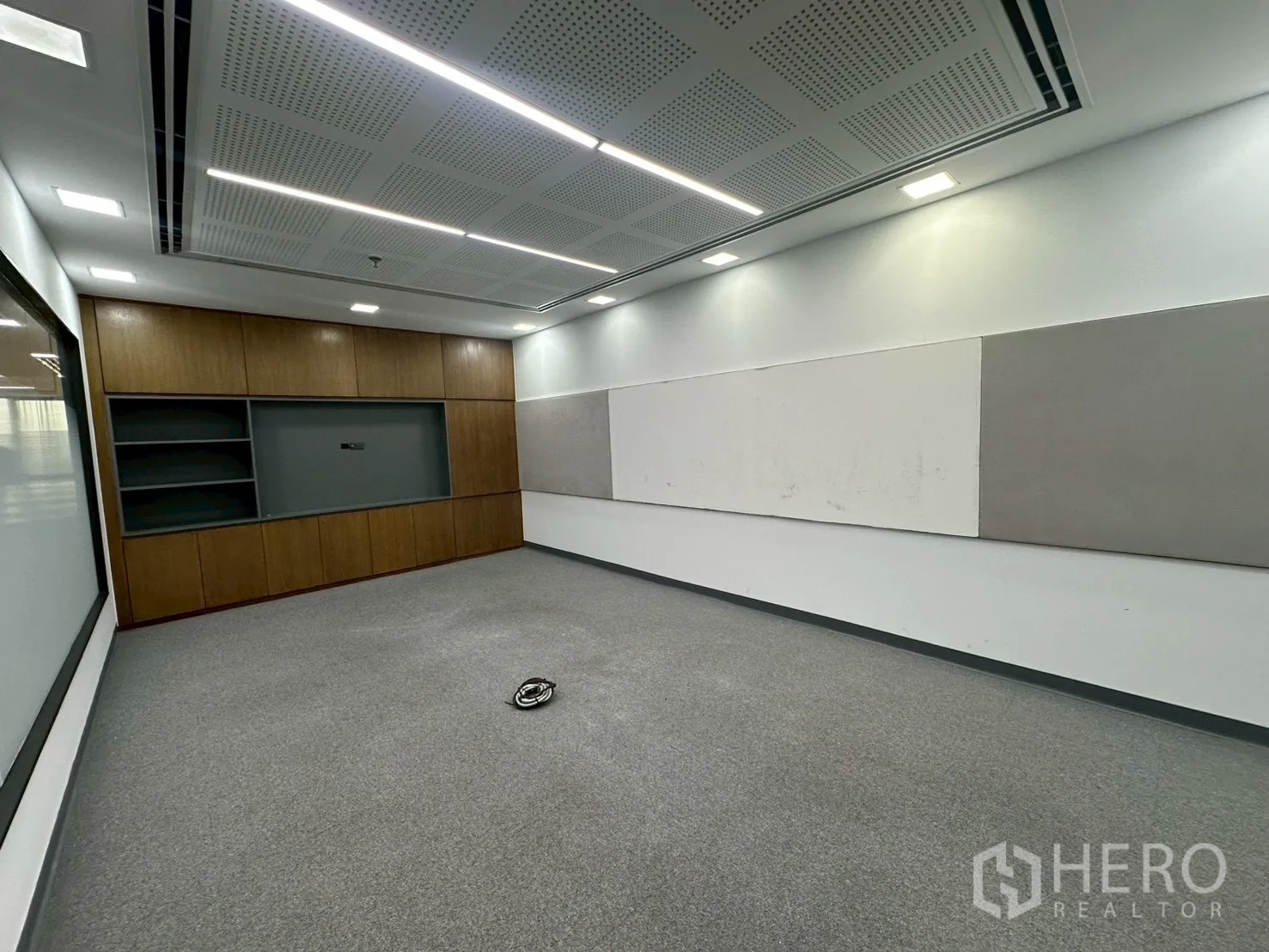 Office Space for rent - Conference room with acoustic ceiling, long whiteboard and wood storage feature.