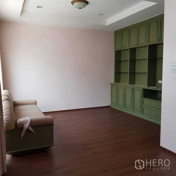 Home Office for rent in Watthana, Bangkok - Family room with built-in green cabinetry and sofa on wood flooring.