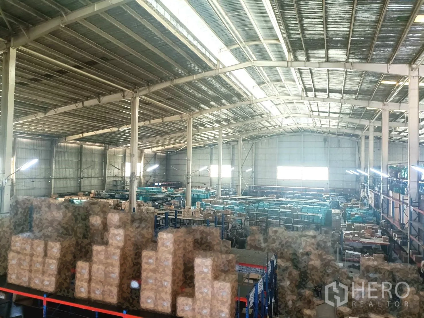 Warehouse for rent in Lam Luk Ka, Pathum Thani - Warehouse interior with high steel roof, skylights, and racking filled with goods.