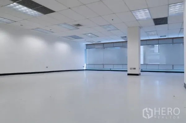 办公空间 出租在Ratchathewi, Bangkok - 开放式145平方米办公室，白色地面，吊顶灯，大幅磨砂窗与中央立柱。