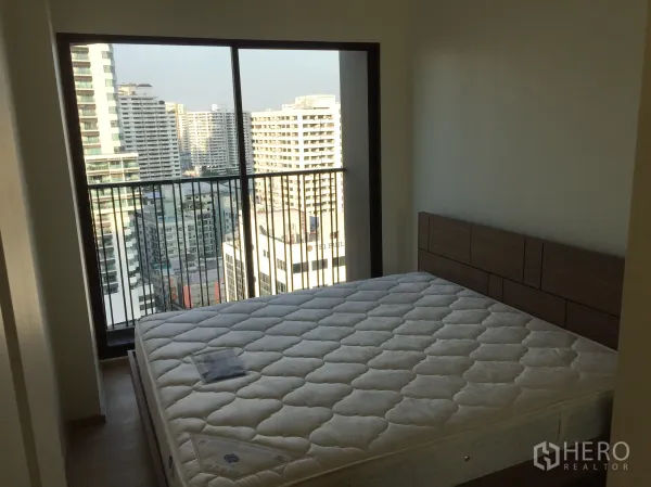 คอนโด ให้เช่าในBangkok - ห้องนอนพร้อมหน้าต่างบานใหญ่และราวระเบียง มองเห็นวิวตึกสูงของเมือง