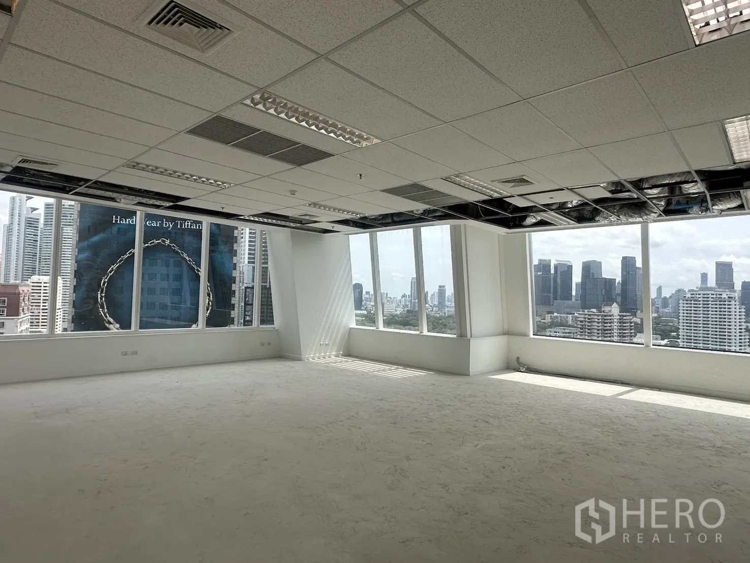 Office Space for rent in Watthana, Bangkok - Corner office area with ceiling grid and natural light streaming across the floor.