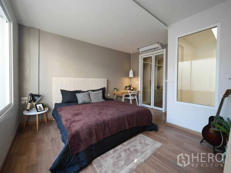 Townhouse for rent in Watthana, Bangkok - Bright master bedroom with wood flooring, large window, work desk and glass door.