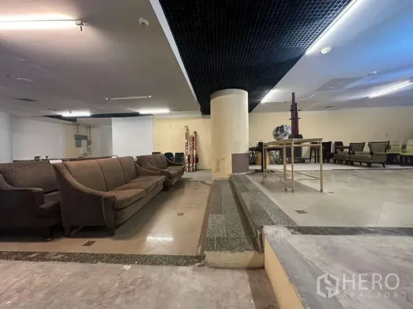 Retail Space for rent - Stair-step change of levels with column, tiled floors and seating zones inside a retail unit.