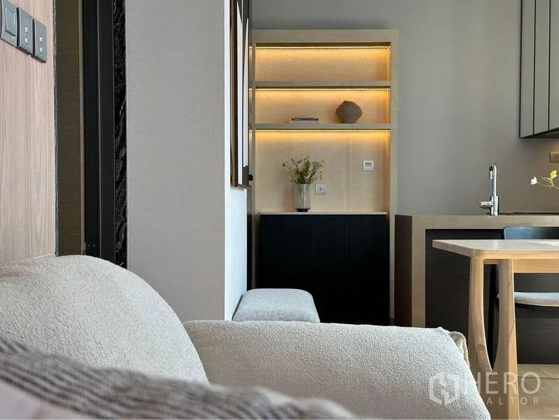 Condominium for rent in Pathum Wan, Bangkok - Built-in shelving with warm LED backlighting beside the sofa and dining table.