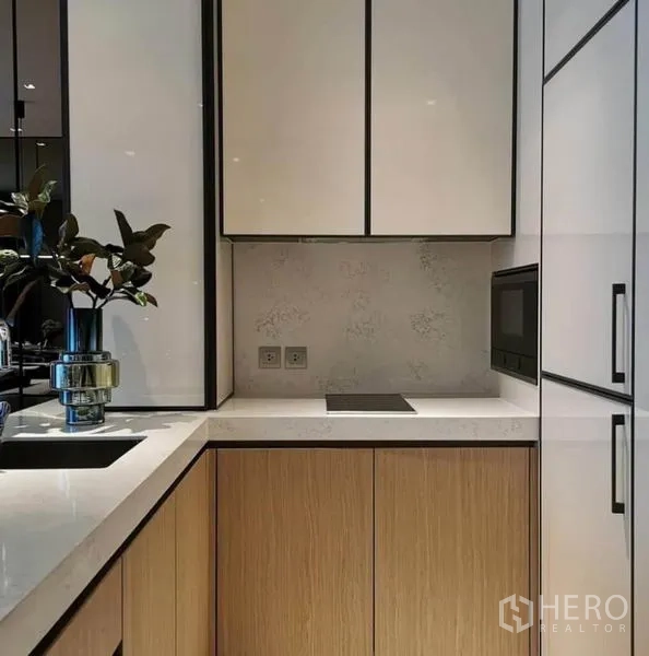 Condominium for rent in Khlong Toei, Bangkok - Compact modern kitchen with induction hob, built-in microwave and ample cabinetry