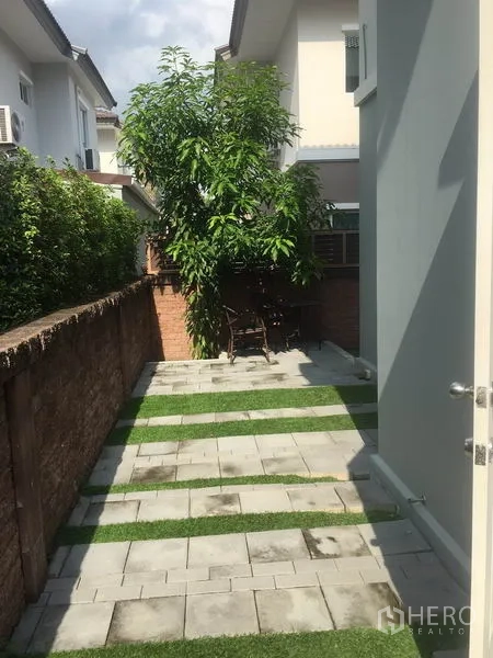 Detached House for rent in Suan Luang, Bangkok - Paved side yard with grass strips, mature tree and brick boundary wall.