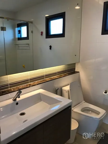 Detached House for rent in Bang Kapi, Bangkok - Second bathroom with large mirror, sink vanity and toilet.