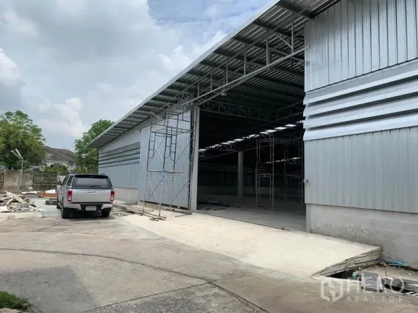 Warehouse for rent in Mueang Pathum Thani, Pathum Thani - Steel-clad warehouse exterior with wide sliding door, high roof and concrete loading driveway in Mueang Pathum Thani.
