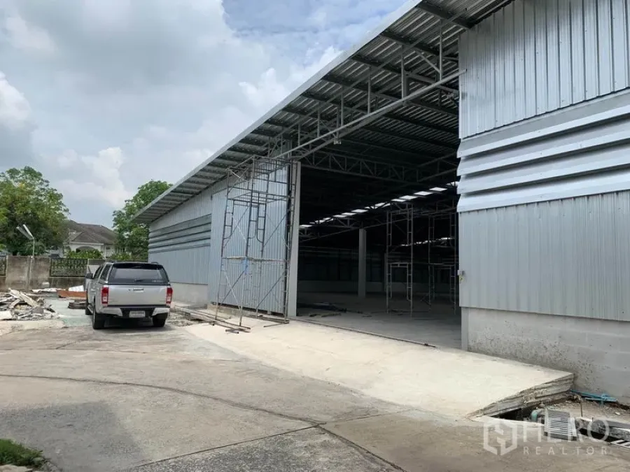 Warehouse for rent in Mueang Pathum Thani, Pathum Thani - Steel-clad warehouse exterior with wide sliding door, high roof and concrete loading driveway in Mueang Pathum Thani.
