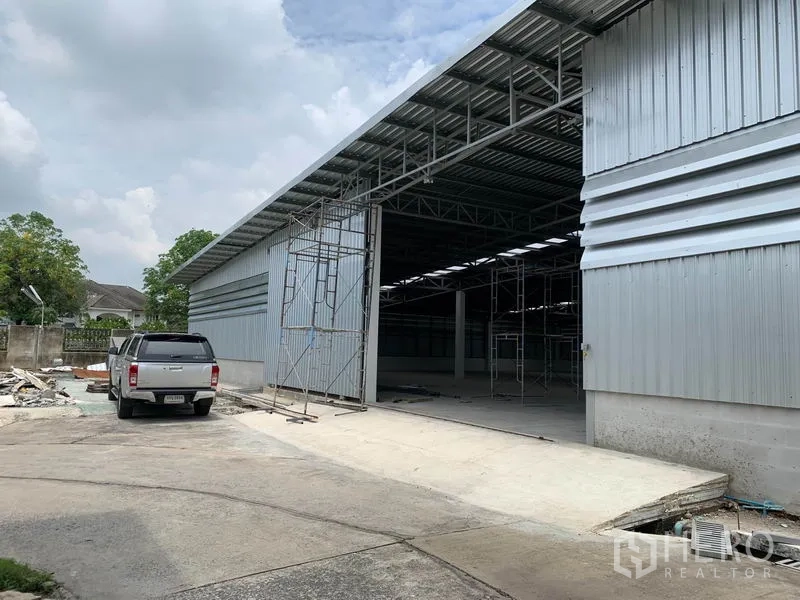 Warehouse for rent in Mueang Pathum Thani, Pathum Thani - Steel-clad warehouse exterior with wide sliding door, high roof and concrete loading driveway in Mueang Pathum Thani.