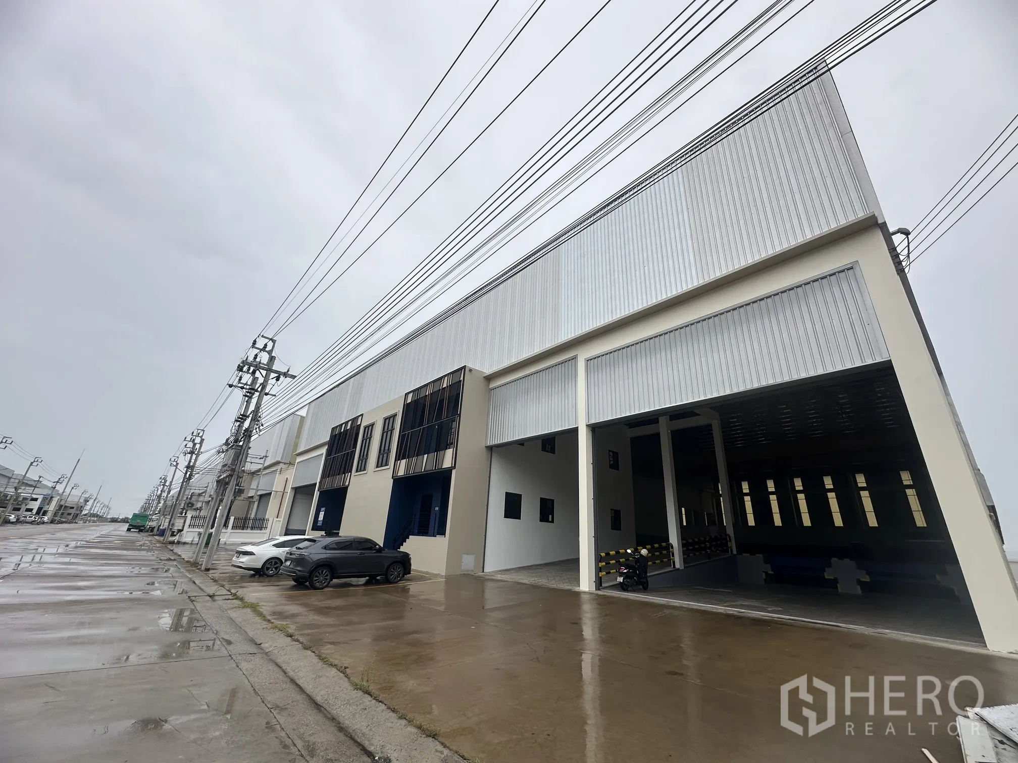 Factory for rent in Bang Phli, Samut Prakan - Modern factory exterior with large covered loading bay and street parking.