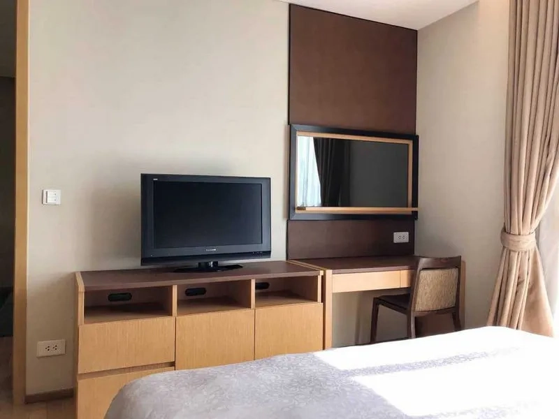 Condominium for rent in Watthana, Bangkok - Bright bedroom with TV console, built-in dressing desk and large curtained window in a Thonglor-area condo.